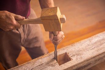 Chiseling a mortise in salvaged wood beam.