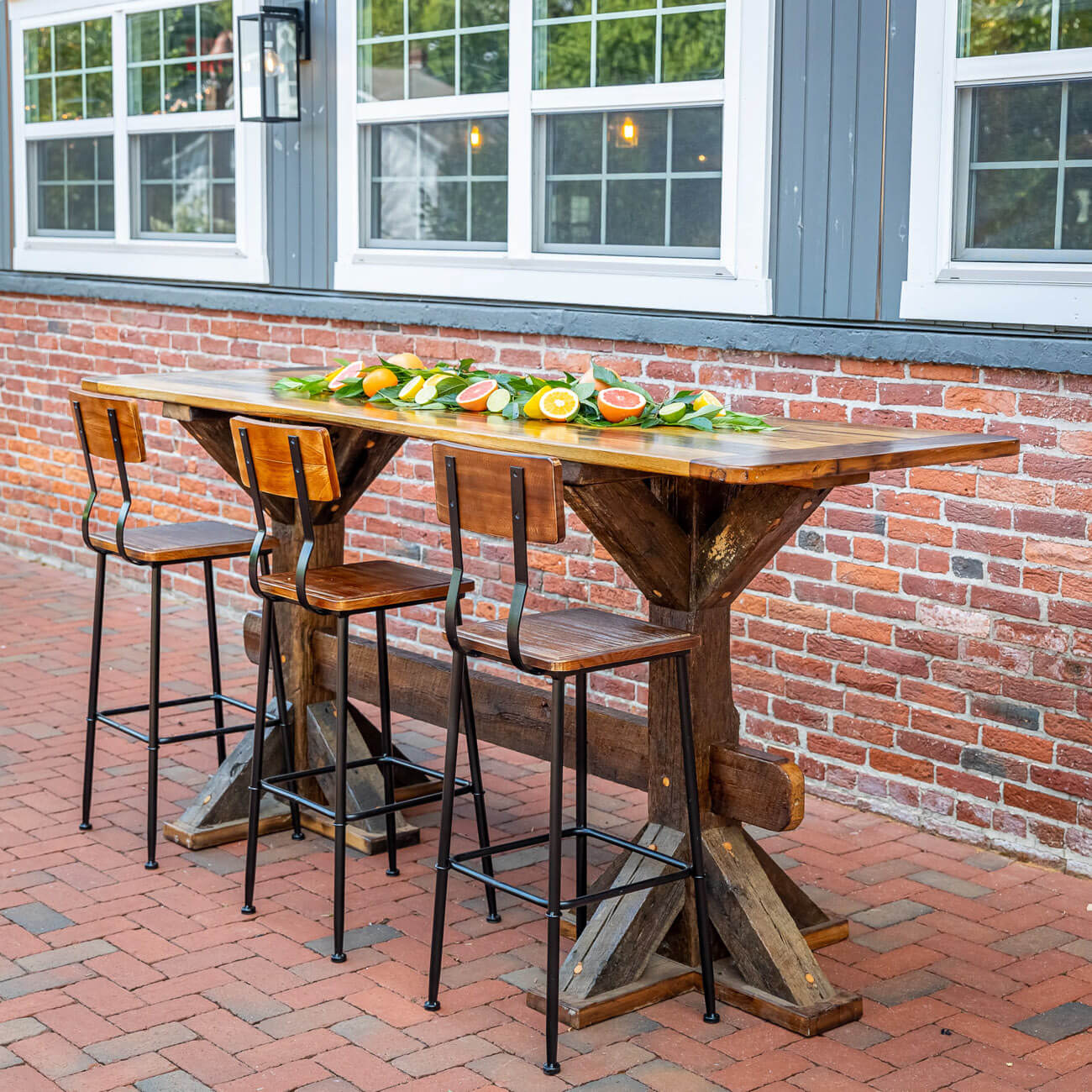 Bar table and stools made with reclaimed barn wood in front of a brick wall