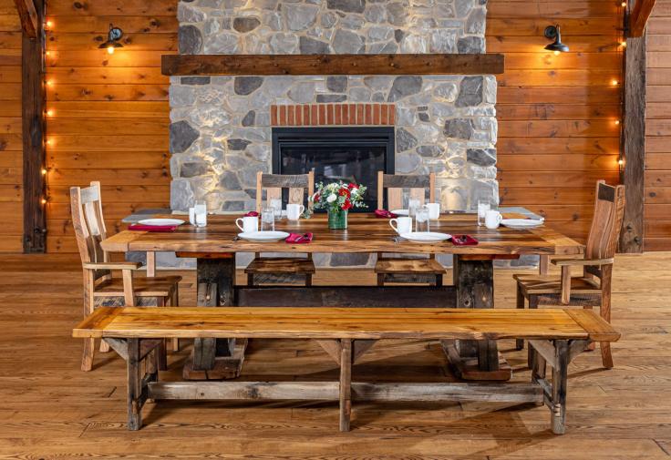  dining table with chairs and bench made with reclaimed wood in front of a stone fireplace